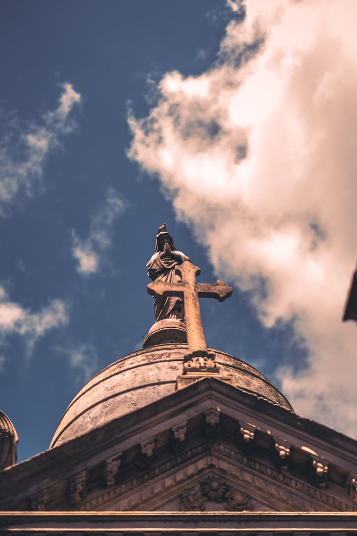 Majestic church cross sculpture against a backdrop of clouds in a low angle view.