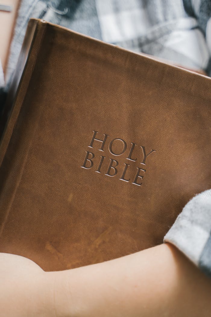 A close-up shot of a leather-bound Holy Bible held in someone's hands, emphasizing faith and spirituality.