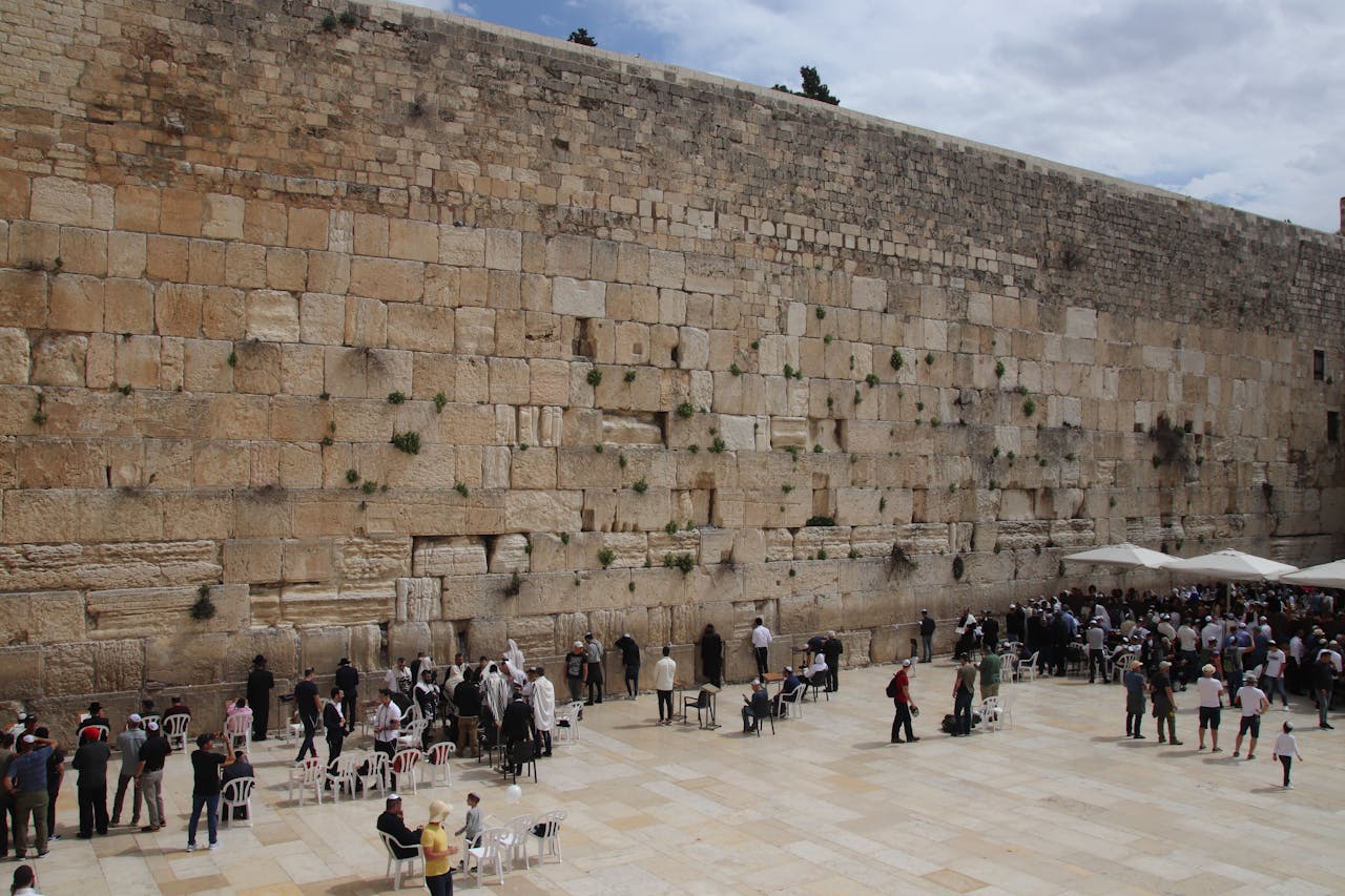 The Western Wall in Jerusalem, a historic and religious site, with visitors gathered for prayer.