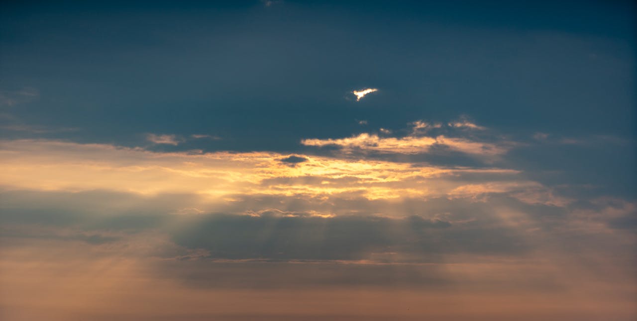 A captivating sunset sky with golden sun rays streaming through clouds, creating a dramatic atmosphere.