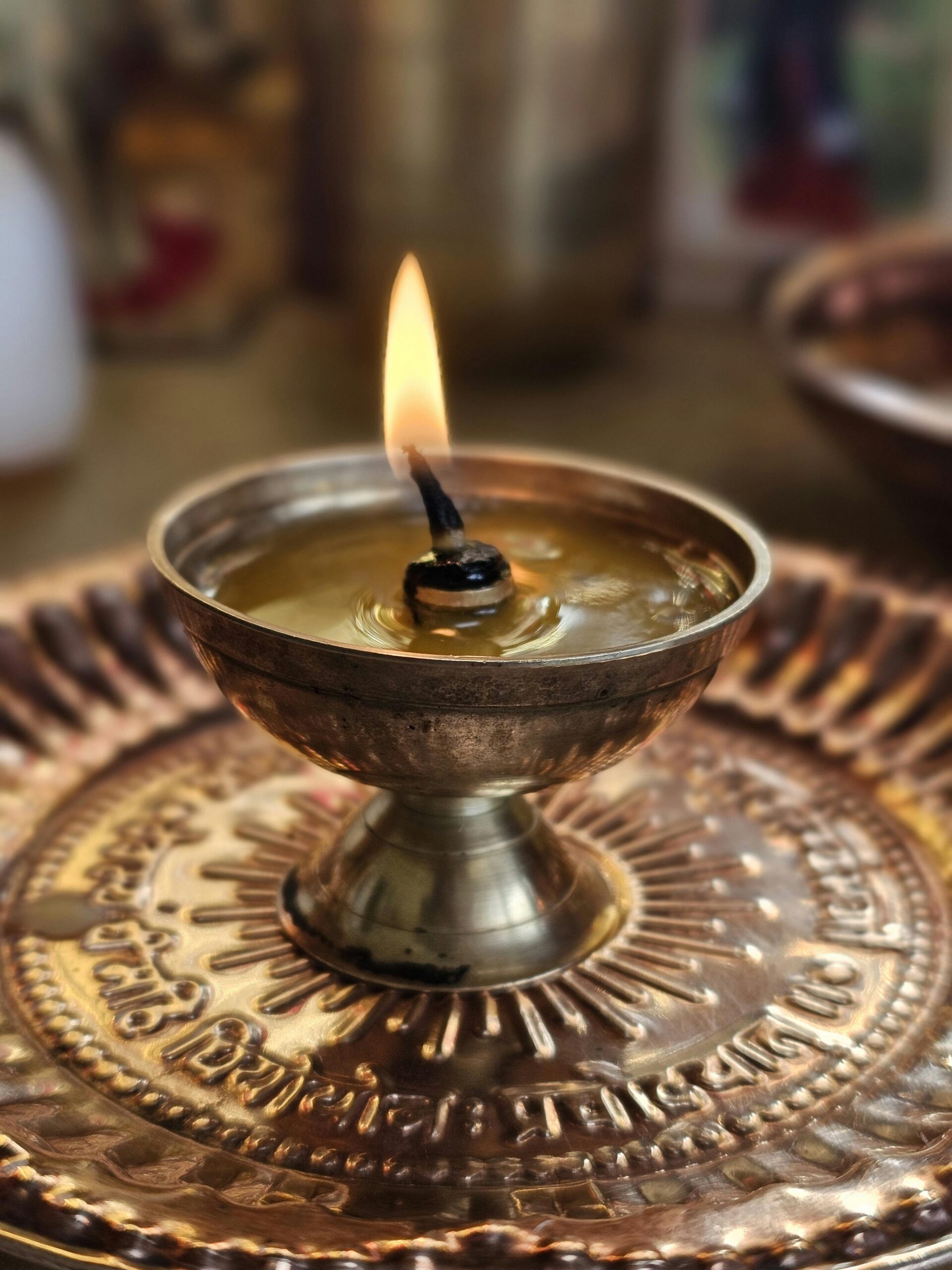 Bronze oil lamp with a flame, symbolizing spirituality and rituals, set on a detailed plate.