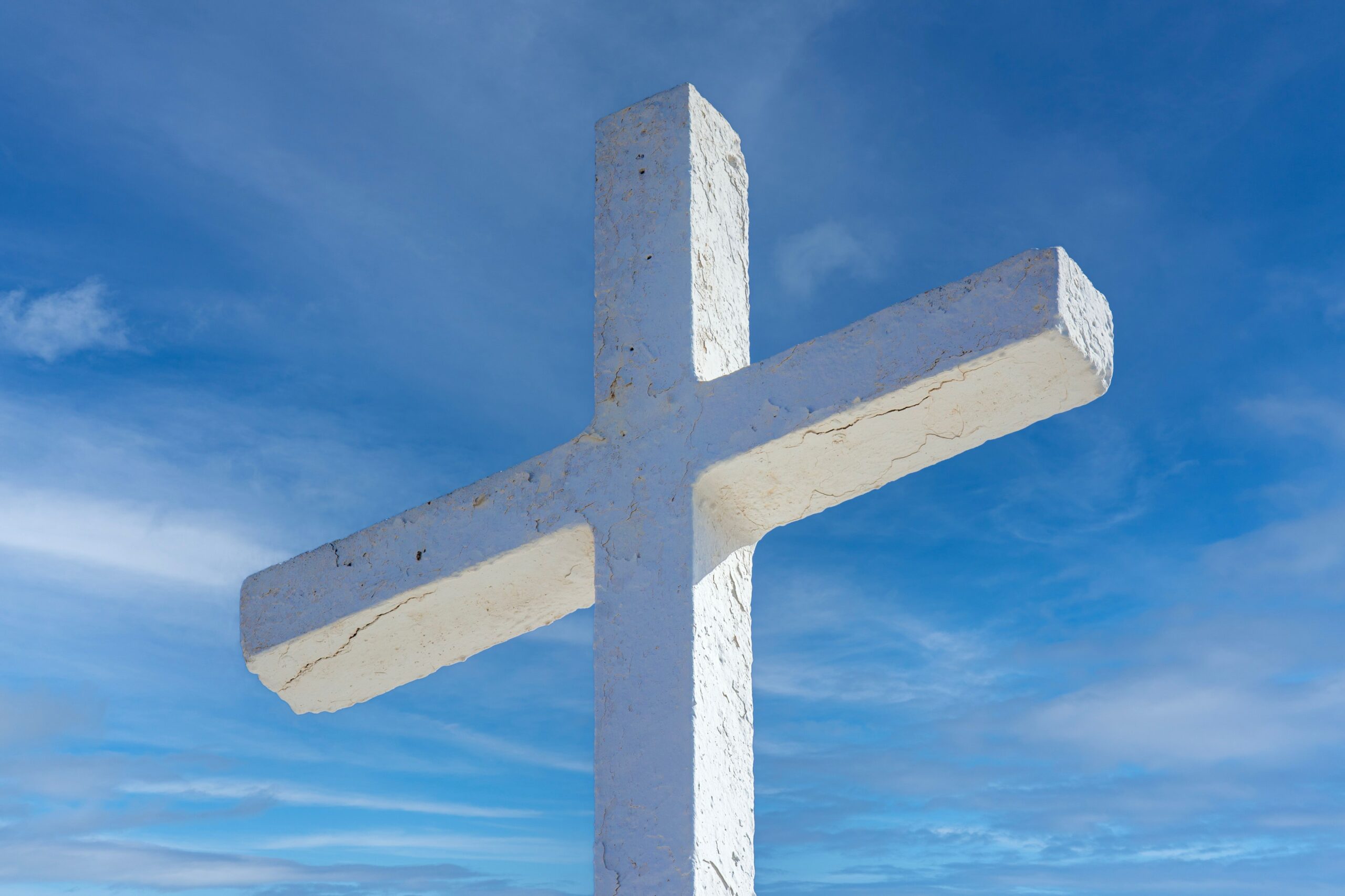 A serene depiction of a white cross against a vibrant blue sky, symbolizing faith and spirituality.